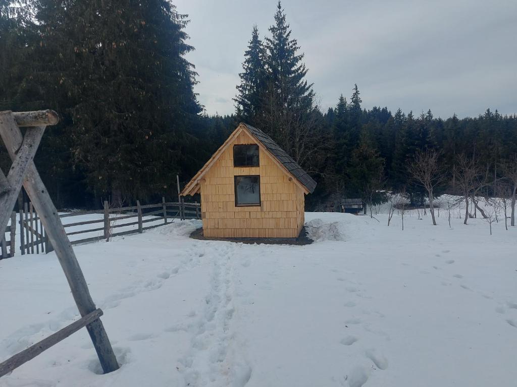 a small wooden cabin in a snow covered field at Studio apartman Planinska Bajka in Olovo