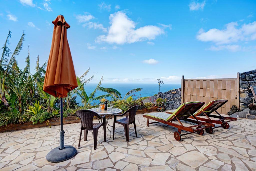 a patio with a table and chairs and an umbrella at Casita Paraiso in Los Quemados