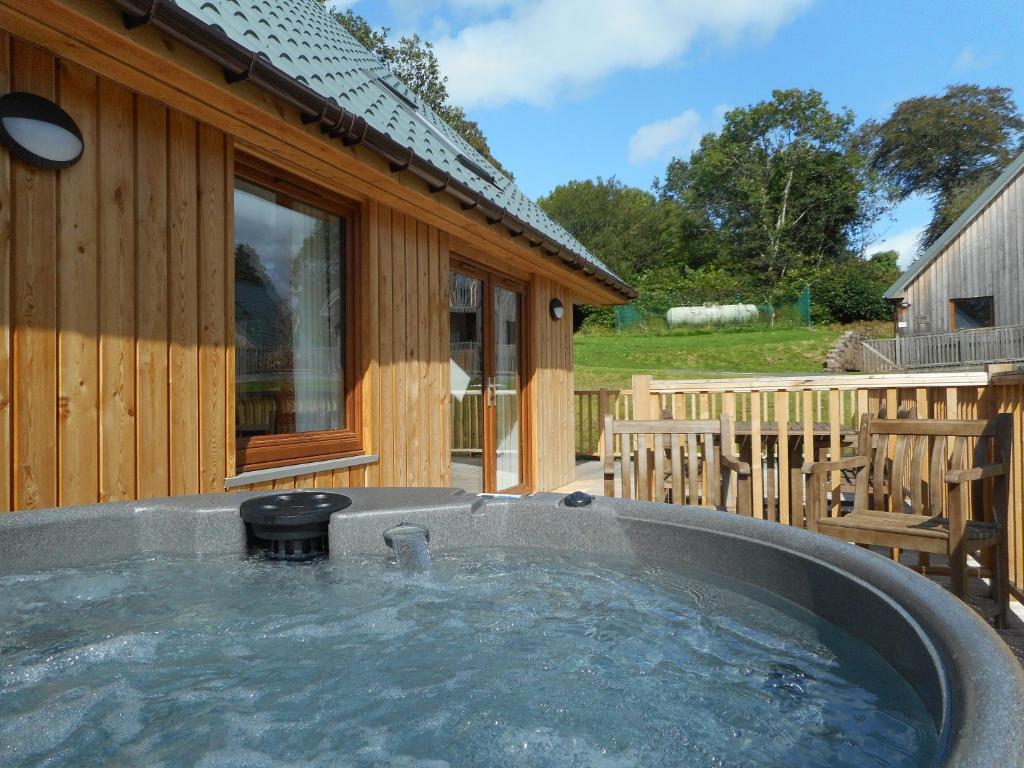 a hot tub in front of a wooden house at Lord Galloway 36 with Hot Tub in Newton Stewart