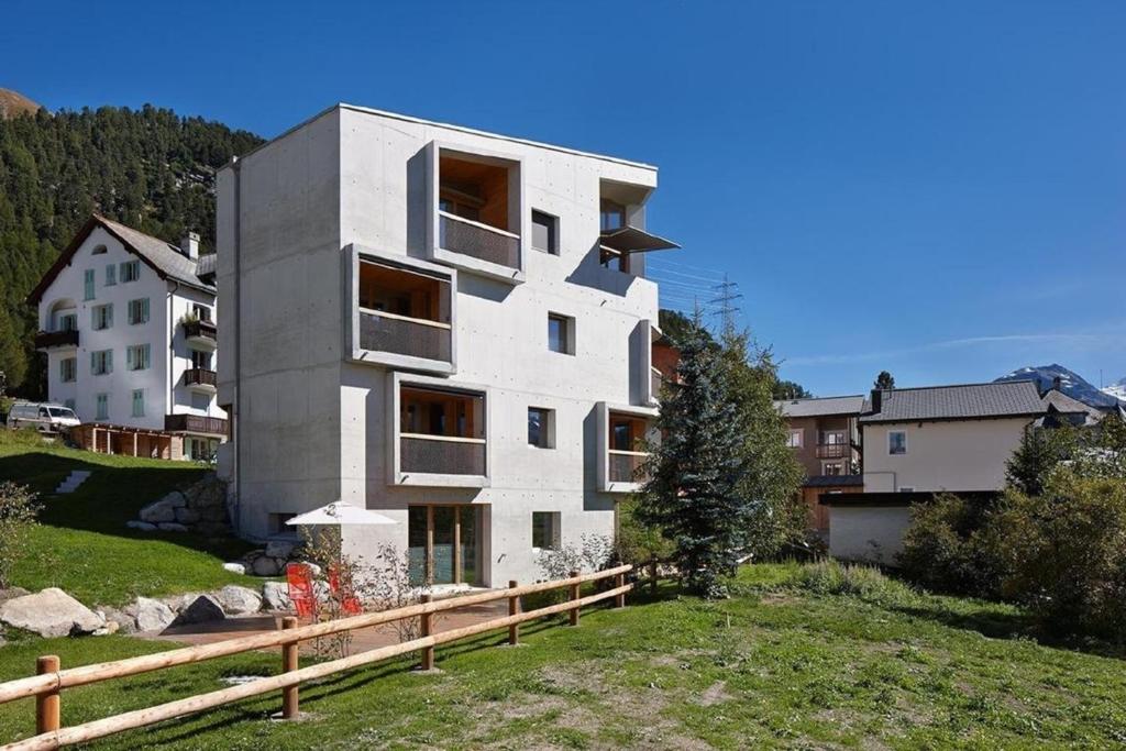 een wit gebouw op een heuvel naast een huis bij Alpine Lodge 4-Bett-Wohnung Chesa Plattner "Bergbahnen All inklusive" im Sommer in Pontresina