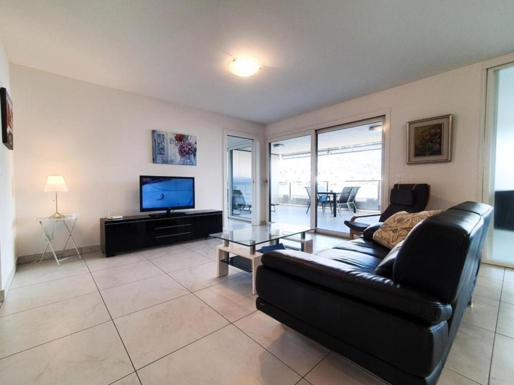 a living room with a black couch and a television at Süsse Wohnung mit bezaubernde Seesicht Apt 405 in Locarno