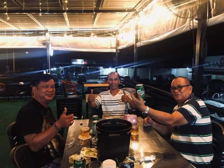 a group of three men sitting at a table at EUC Room Stay in Tuaran