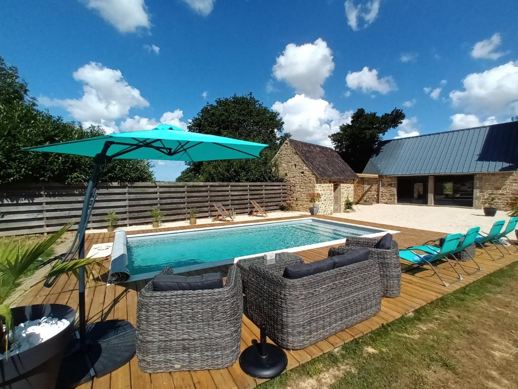 - une piscine avec un parasol bleu, des chaises et une table dans l'établissement Gîte avec piscine, à Mantallot