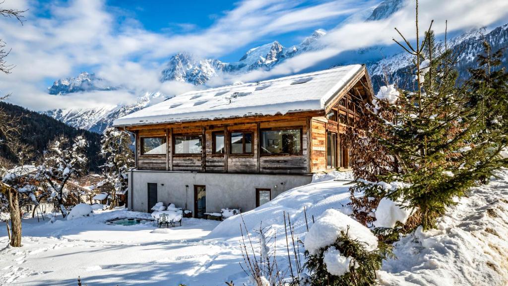 een huis in de sneeuw met bergen op de achtergrond bij Chalet Léandre in Les Houches