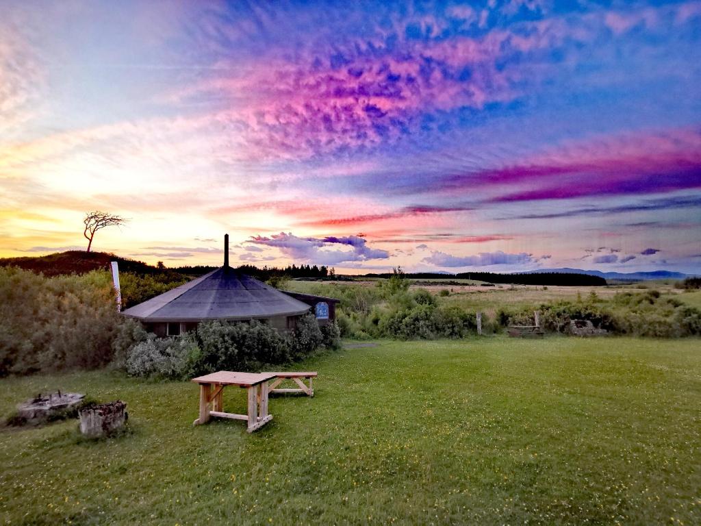 a picnic bench in a field with a sunset at The Round House in Newton Stewart