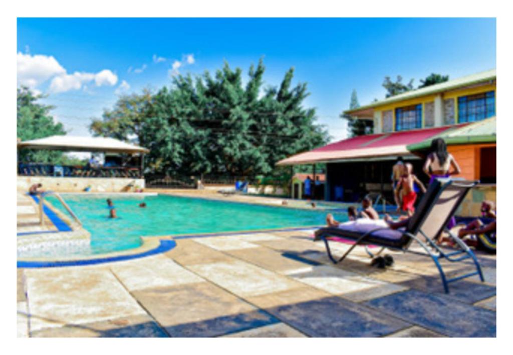 un grupo de personas sentadas en una silla junto a una piscina en Rozala Motel, en Bondo