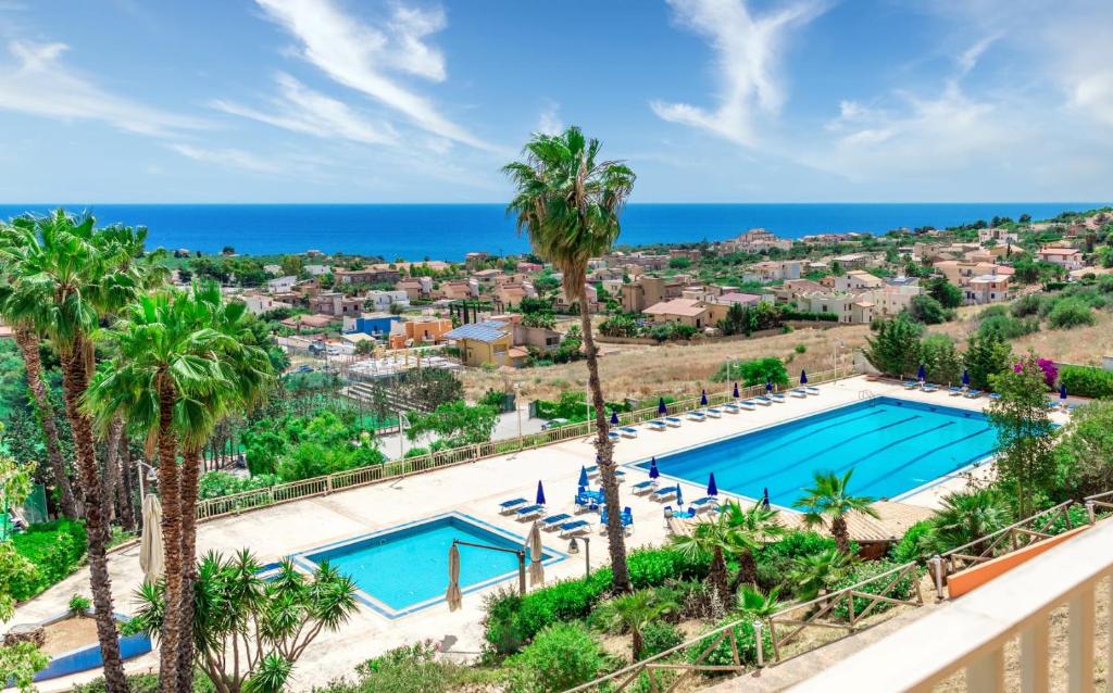 uma vista aérea de uma piscina com palmeiras e do oceano em !!! PADEL - PISCINA - CALCIO !!! - Aparthotel Isabella em Sciacca
