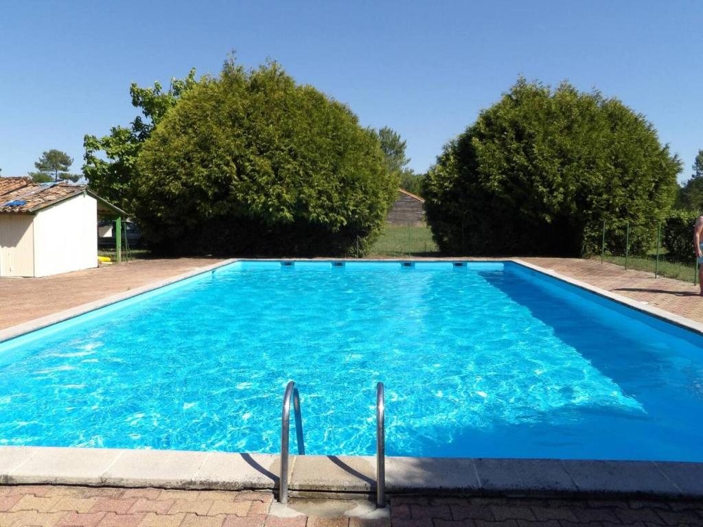 ein blauer Pool mit Bäumen im Hintergrund in der Unterkunft Duplex en residence tennis piscine in Naujac-sur-Mer