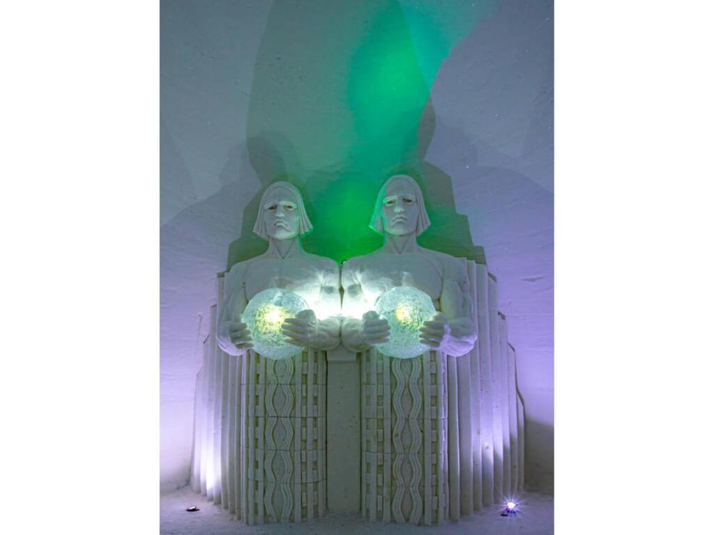 two statues of two people holding lights in their hands at Lapland Hotels SnowVillage in Kittilä