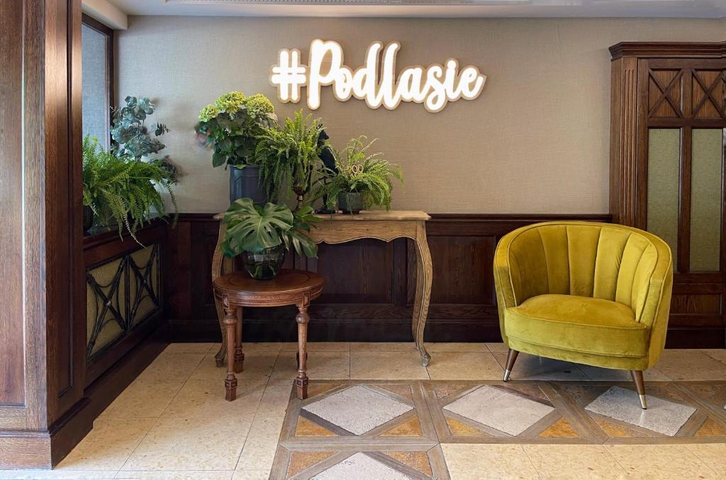 a waiting room with a yellow chair and a sign at Hotel Podlasie in Białystok