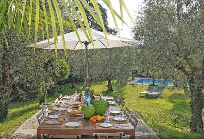 a long wooden table with plates and fruit on it at Villa Sweet Flower - with Private Pool and Garden in Manerba del Garda