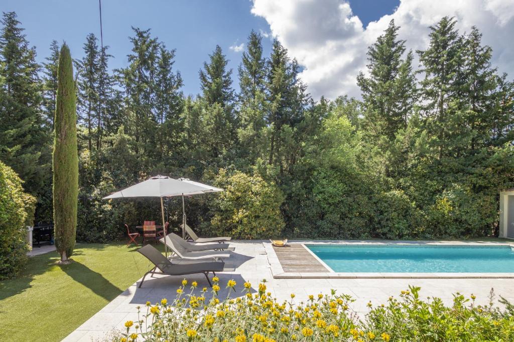 einen Hinterhof mit Pool und Sonnenschirm in der Unterkunft Villa Enzo in Orgon