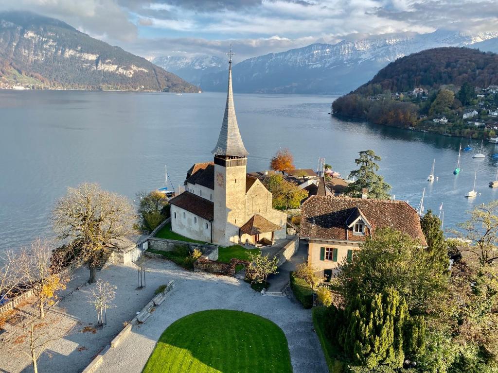 an island in the middle of a lake with a church at Seaside-Lodge, Top Apartment in Spiez