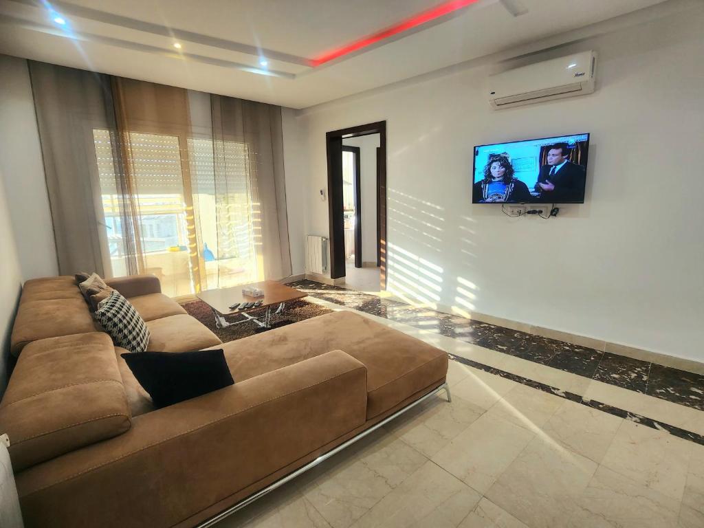 a living room with a couch and a flat screen tv at Accueillant S+1 jardin de carthage in Tunis