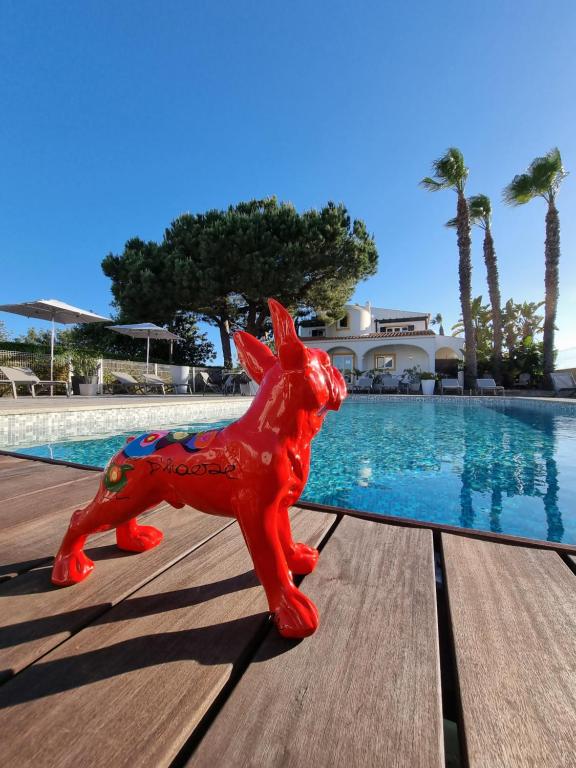 Una estatua de un perro rojo sentado junto a una piscina. en Casa Bela Moura, Boutique Hotel & Wine, en Porches