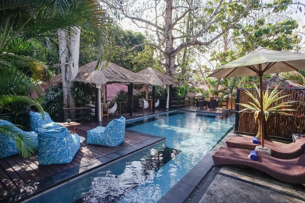 a pool with chairs and umbrellas in a yard at Kampung 168 in Jimbaran