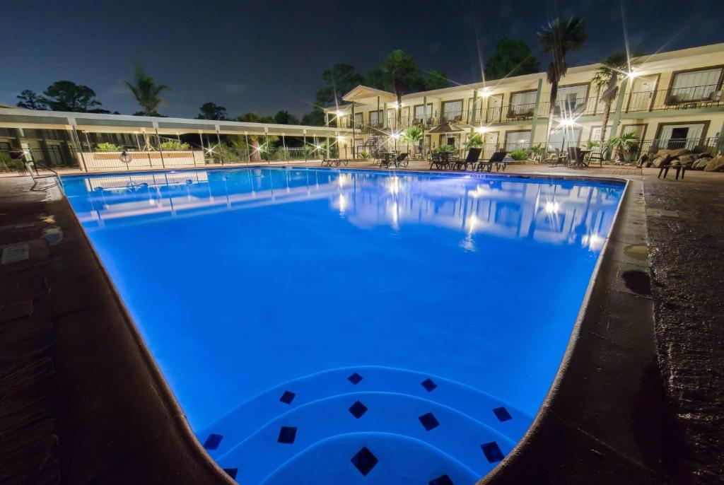 a large swimming pool at night with blue illumination at Ramada by Wyndham Houston Intercontinental Airport East in Humble