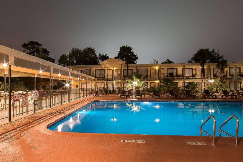 a large pool in front of a hotel at night at Ramada by Wyndham Houston Intercontinental Airport East in Humble
