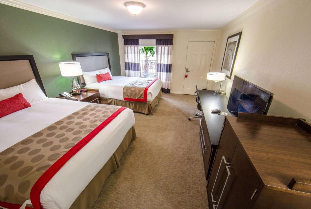 a hotel room with two beds and a flat screen tv at Ramada by Wyndham Houston Intercontinental Airport East in Humble