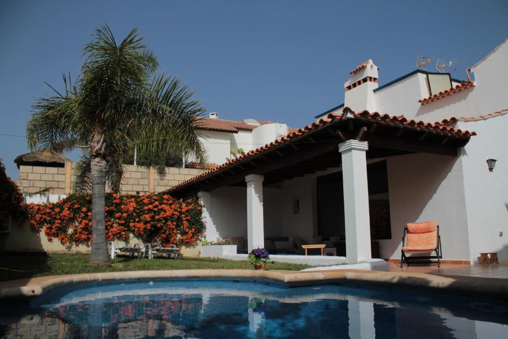 a villa with a swimming pool in front of a house at La Tortuga Hostel in Adeje