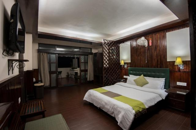 um quarto com uma cama grande e uma televisão em The Nettle and Fern Hotel Gangtok em Gangtok