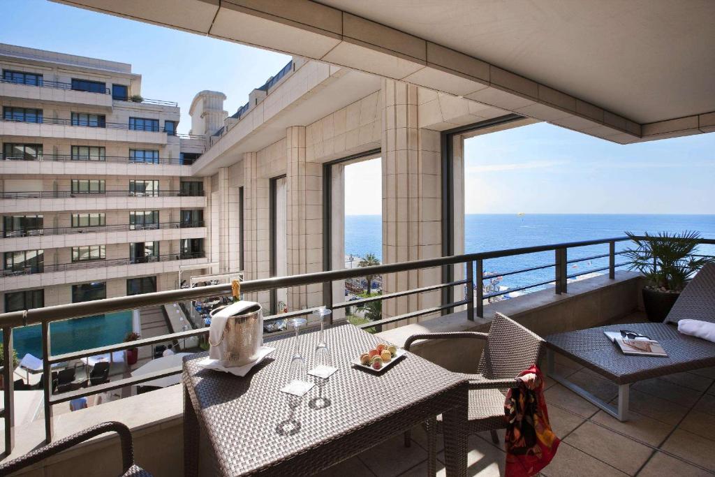 a balcony with a table and chairs with a view of the ocean at Hyatt Regency Nice Palais de la Méditerranée in Nice