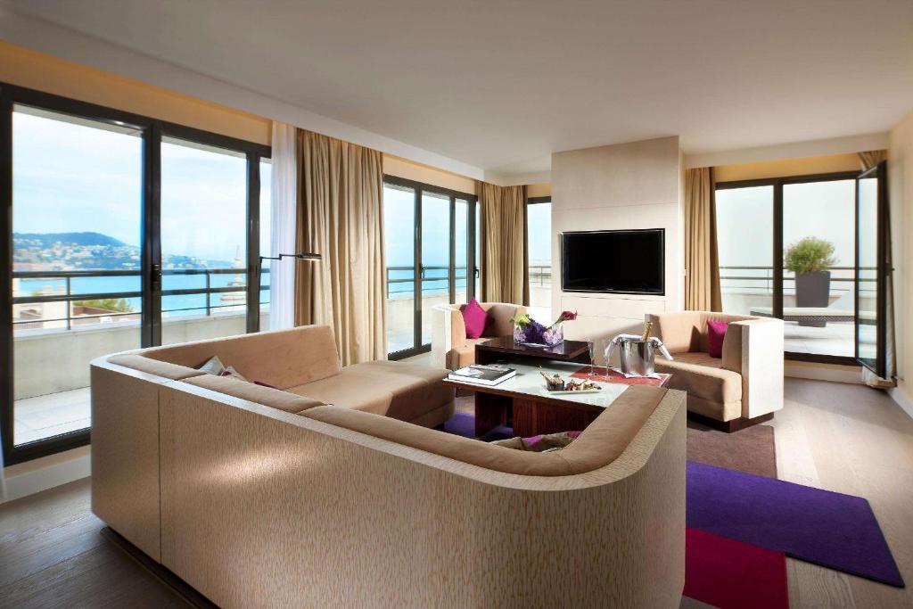 a living room with a couch and chairs and a television at Hyatt Regency Nice Palais de la Méditerranée in Nice