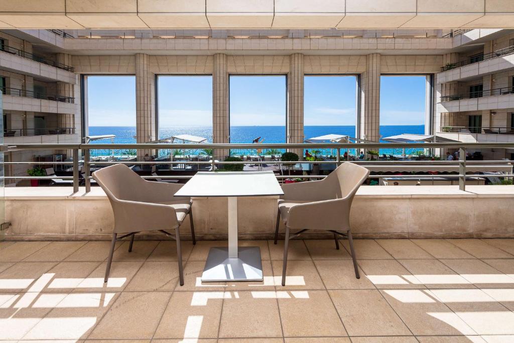 a table and chairs in a building with windows at Hyatt Regency Nice Palais de la Méditerranée in Nice