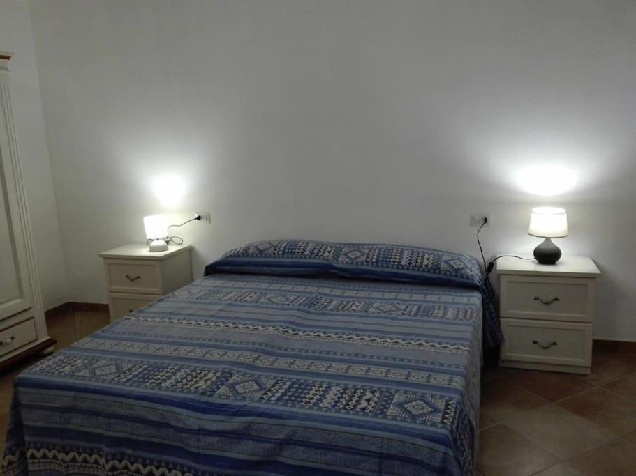 um quarto com uma cama e duas mesas de cabeceira com candeeiros em Villetta relax em SantʼAnna Arresi