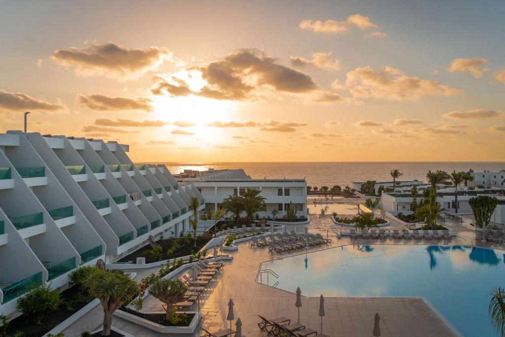 コスタ・テギセにあるRadisson Blu Resort, Lanzarote Adults Onlyの夕日時のリゾートのプールの景色を望めます。