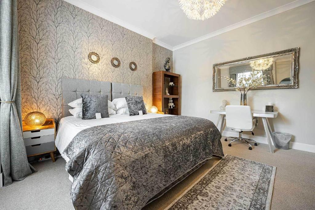 a bedroom with a bed and a desk and a mirror at Carmel Apartments in Falkirk
