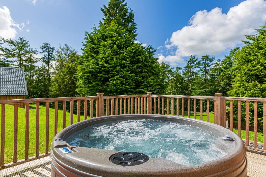bañera de hidromasaje en una terraza con una valla de madera en Lord Galloway 37 with Hot Tub, en Newton Stewart