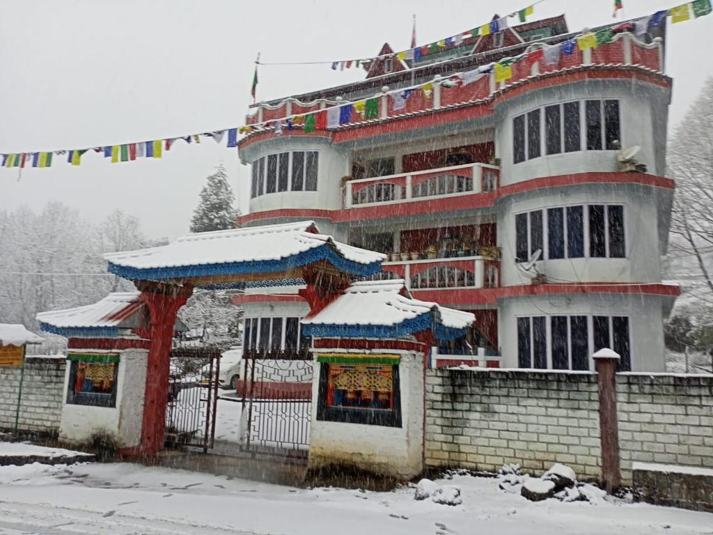 Un edificio nella neve con le bandiere sopra. di Enchanting Tawang a Tawang