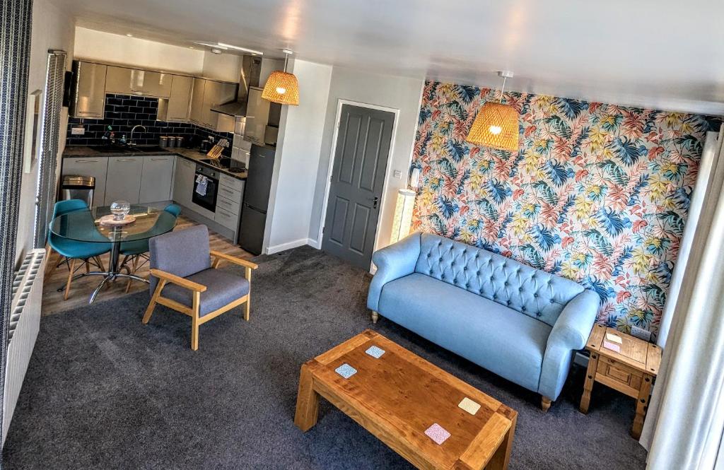 a living room with a blue couch and a table at Stylish penthouse apartment in Ramsgate