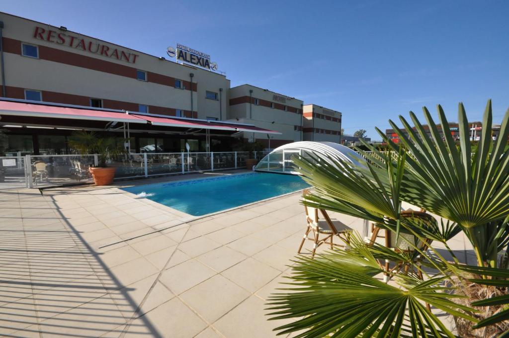 uma piscina em frente a um edifício em The Originals City, Hôtel Alexia, La Souterraine (Inter-Hotel) em La Souterraine