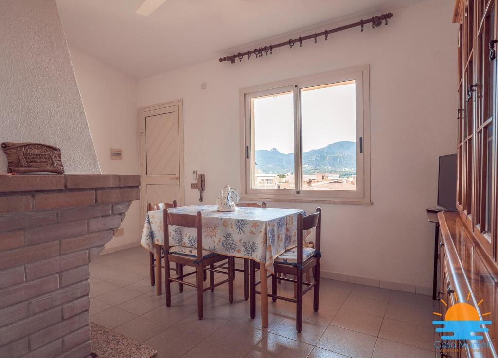 una sala da pranzo con tavolo, sedie e finestra di Casa Mameli Apartment Villasimius a Villasimius
