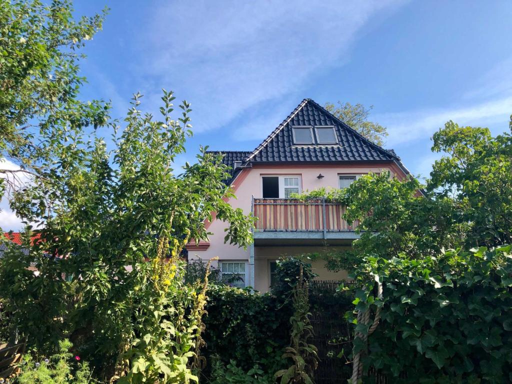 Casa rosa con balcón y árboles en Ferienwohnung Sonnensuite, en Wustrow