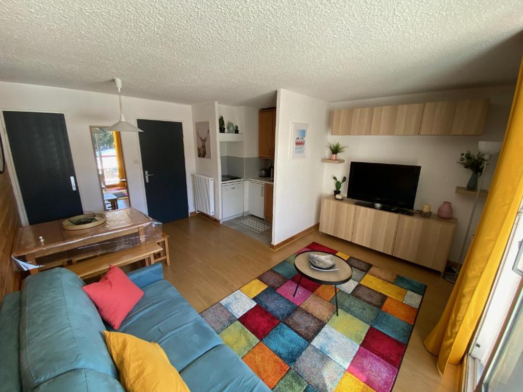 a living room with a blue couch and a colorful rug at APPARTEMENT RÉNOVE, RÉSIDENCE COTE BRUNE, CENTRE STATION, PIED DES PISTES, 30m² 4/5 pers in Les Deux Alpes