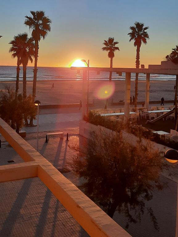 a sunset over a beach with palm trees and the ocean at FiveStepsToSea - Beach Apartment Valencia in Valencia