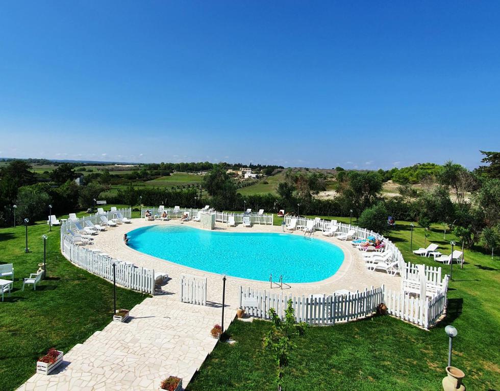 una grande piscina con sedie bianche intorno di Agriturismo La Rondine a Otranto