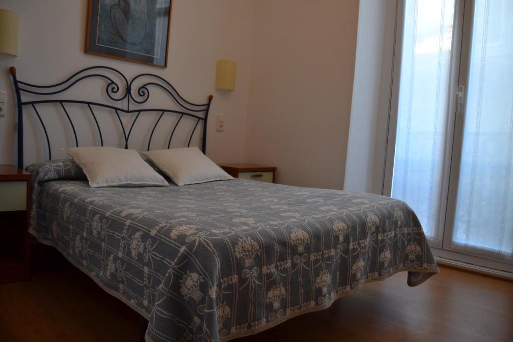 a bedroom with a bed with a blanket and a window at Pensión San Telmo / San Juan in San Sebastián