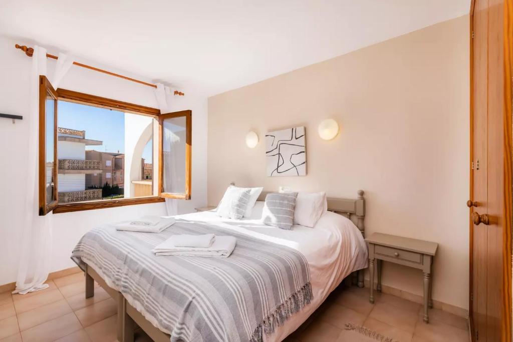 a bedroom with a bed with white sheets and a window at Apartamentos Can Salas in Cala Figuera