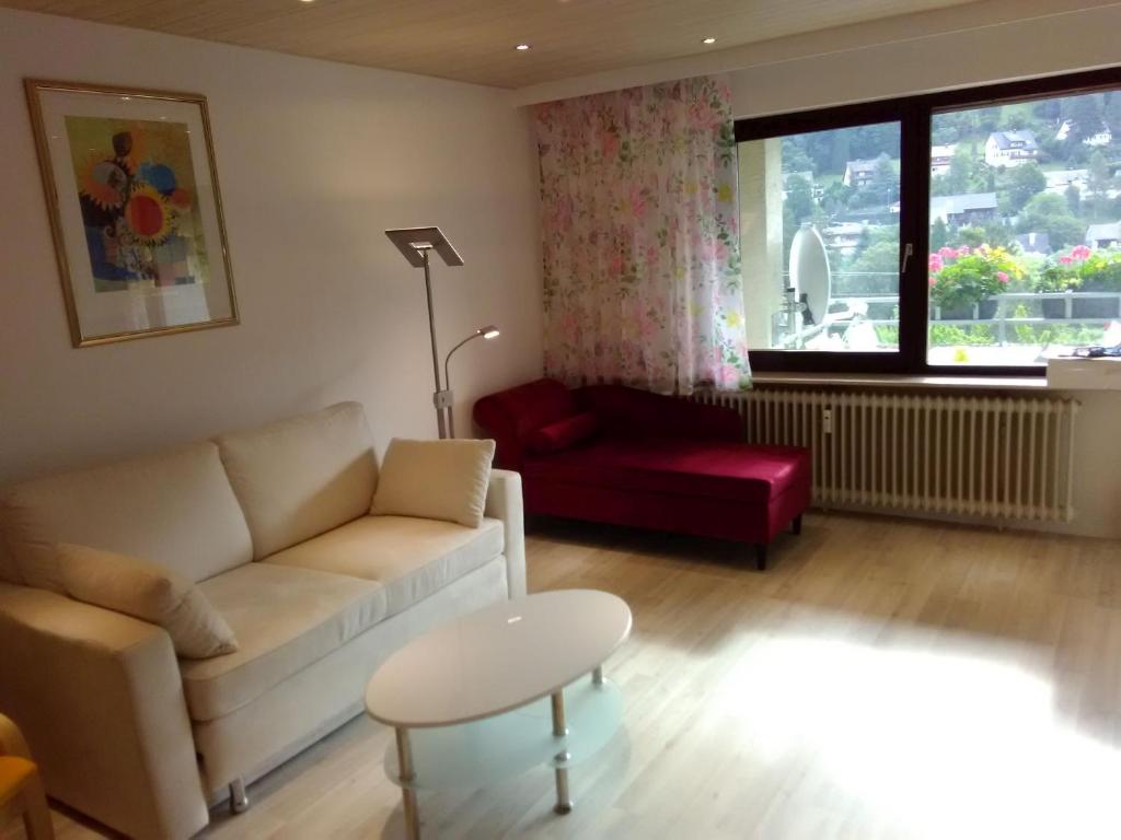 a living room with a couch and a red chair at Ferienwohnung Talblick mit Schwimmbad in Bad Wildbad