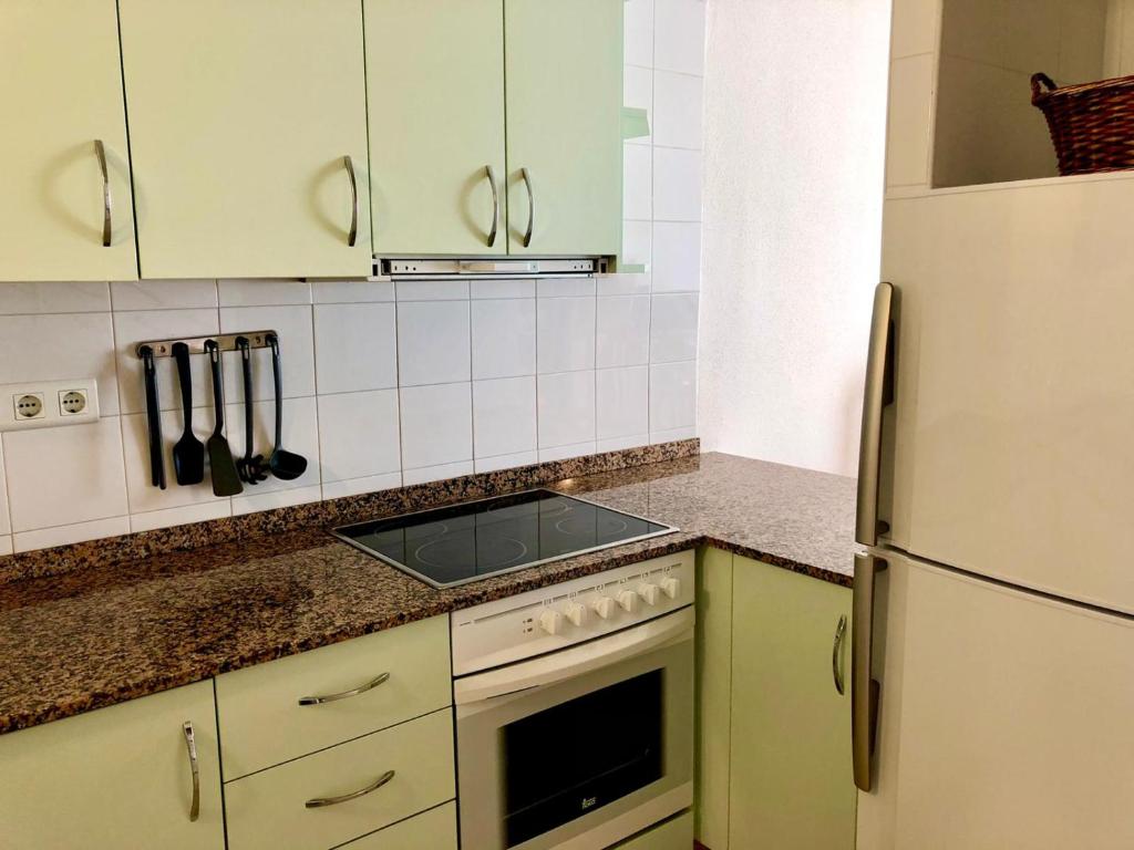 a kitchen with green cabinets and a white refrigerator at Duplex Ancla in L'Ametlla de Mar