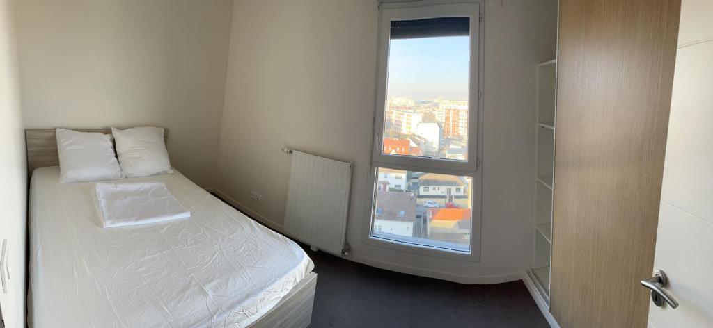 a small bedroom with a bed and a window at Appartement de Romainville in Romainville