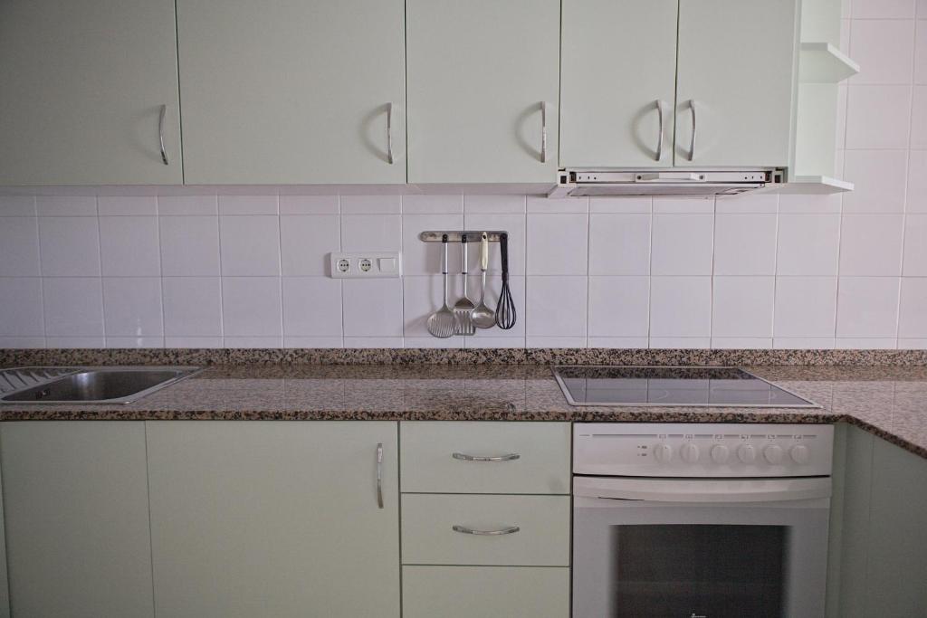 a kitchen with white cabinets and a stove top oven at Duplex Ancla in L'Ametlla de Mar