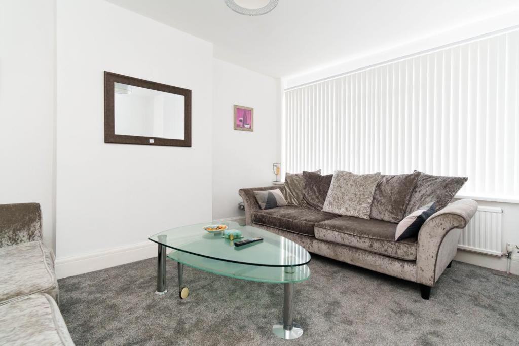 a living room with a couch and a glass table at Foxwood Stays in Leeds