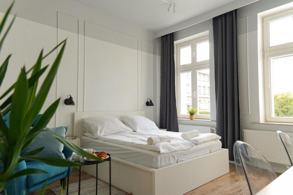 a white bedroom with a bed and a plant at RJ Family Sopot in Sopot