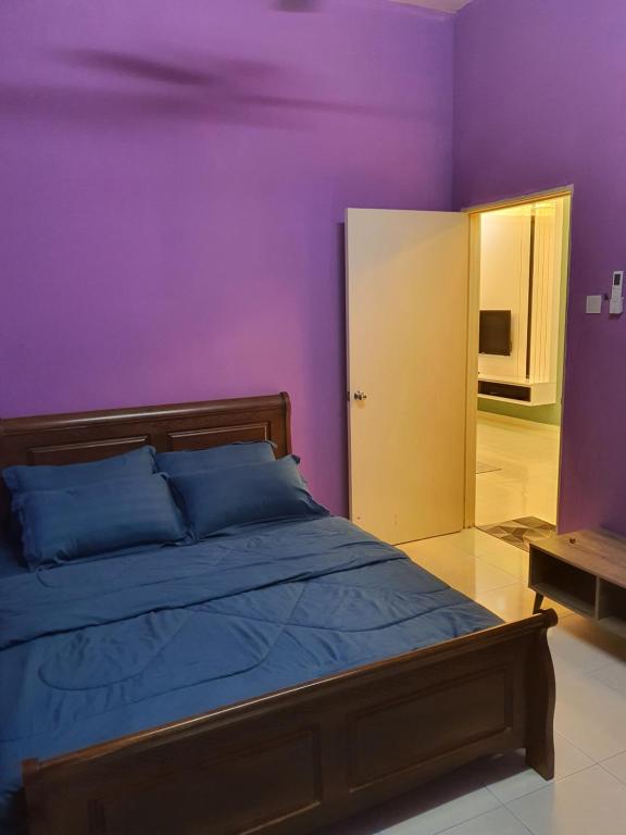 a bedroom with purple walls and a bed with blue pillows at Homestay Layang in Masai