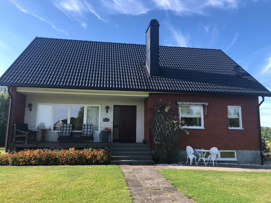 una casa de ladrillo rojo con 2 sillas en el porche en Villa på lantlig idyll i Källunga, Herrljunga, en Herrljunga